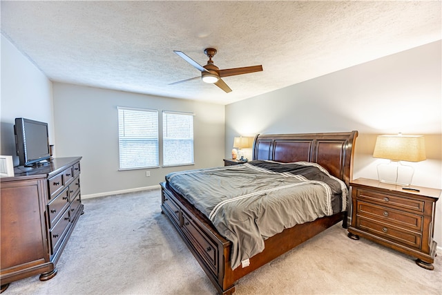 bedroom with ceiling fan, light colored carpet, and a textured ceiling