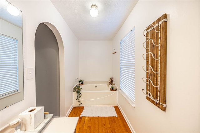 bathroom featuring a wealth of natural light, a washtub, a textured ceiling, and hardwood / wood-style flooring