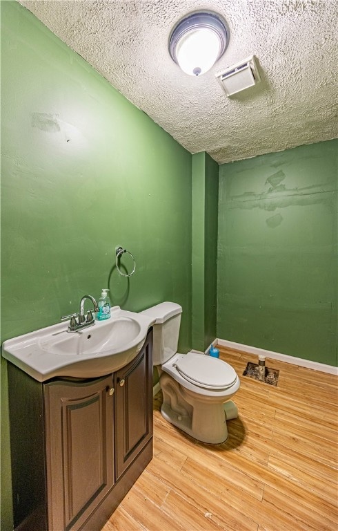 bathroom with toilet, vanity, a textured ceiling, and hardwood / wood-style flooring