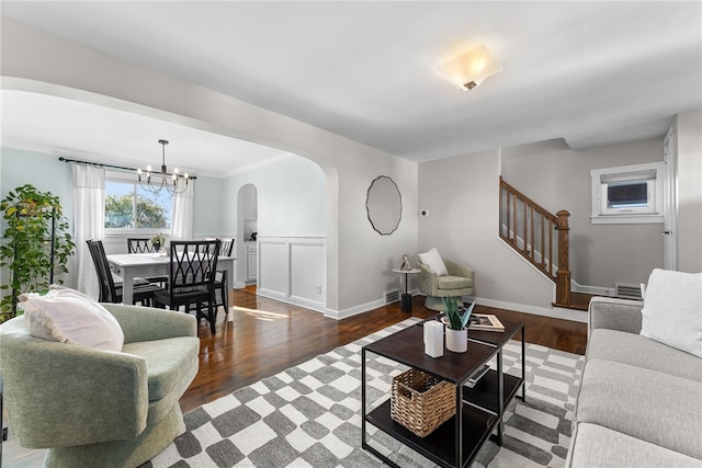 living room featuring dark hardwood / wood-style flooring, crown molding, and an inviting chandelier