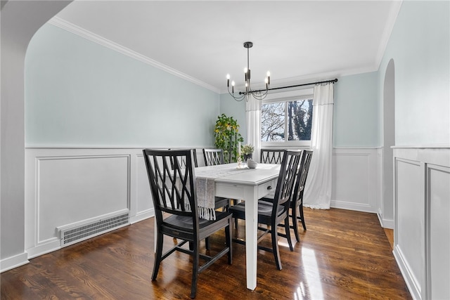 dining space featuring dark hardwood / wood-style floors, ornamental molding, and a chandelier