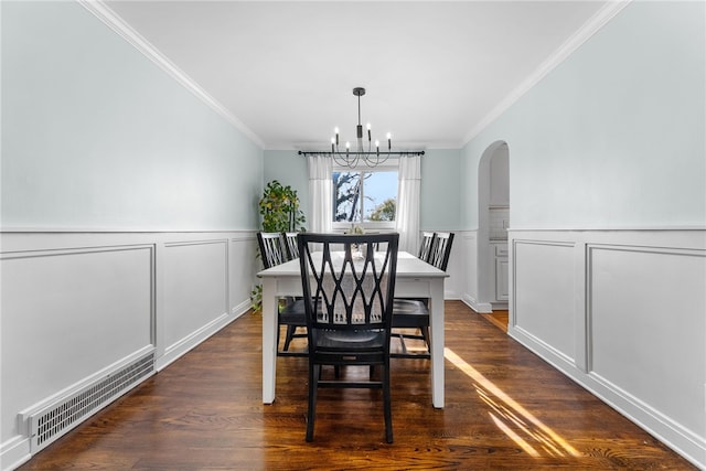 dining space with ornamental molding, dark wood-type flooring, and a chandelier