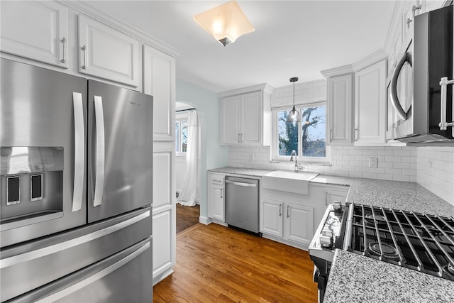 kitchen with white cabinetry, sink, appliances with stainless steel finishes, and light hardwood / wood-style flooring