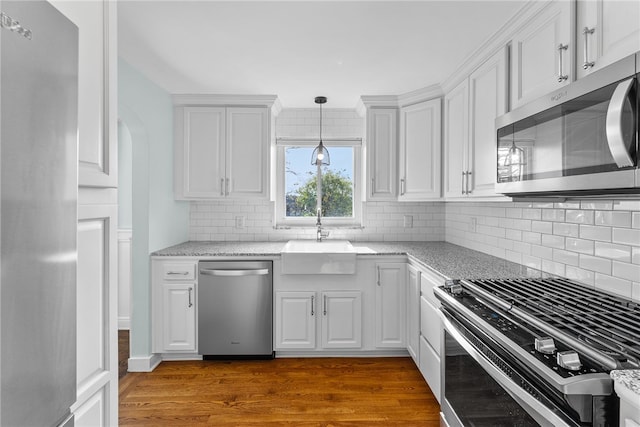 kitchen featuring white cabinetry, sink, dark wood-type flooring, tasteful backsplash, and appliances with stainless steel finishes