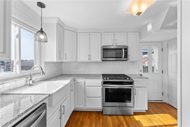 kitchen with white cabinets, stainless steel appliances, a wealth of natural light, and light hardwood / wood-style flooring