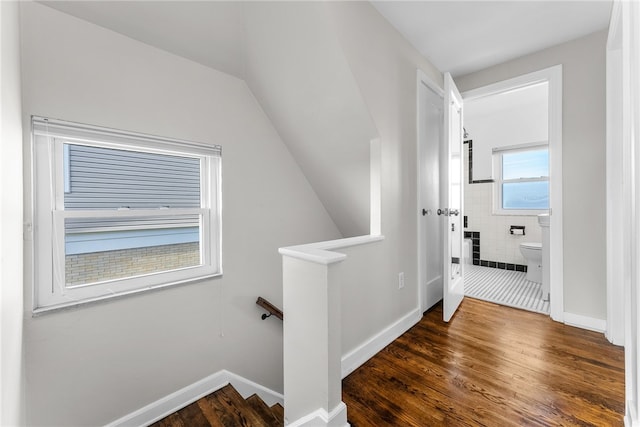 hallway featuring dark hardwood / wood-style flooring, tile walls, and vaulted ceiling