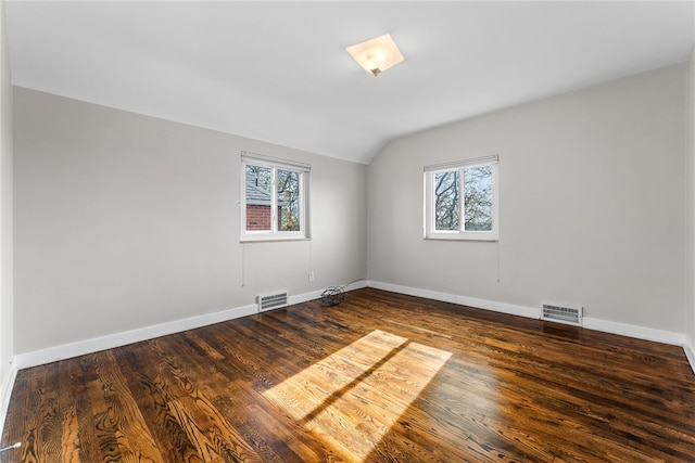 spare room with dark hardwood / wood-style floors, a healthy amount of sunlight, and lofted ceiling