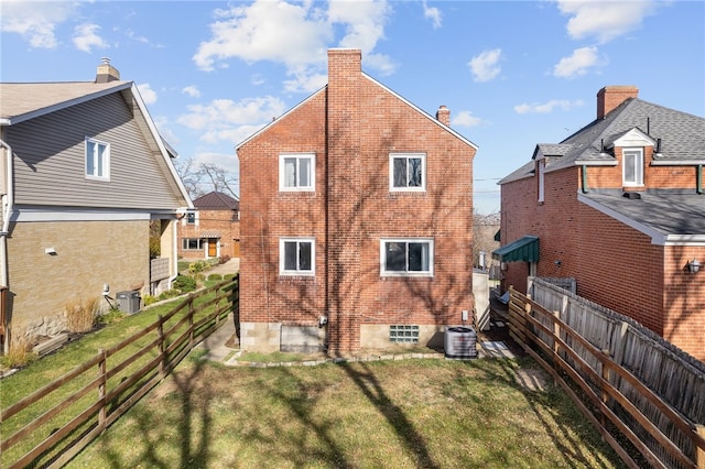 rear view of property with a lawn and central air condition unit