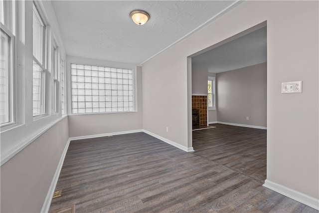 spare room featuring a tile fireplace, a textured ceiling, and dark hardwood / wood-style flooring