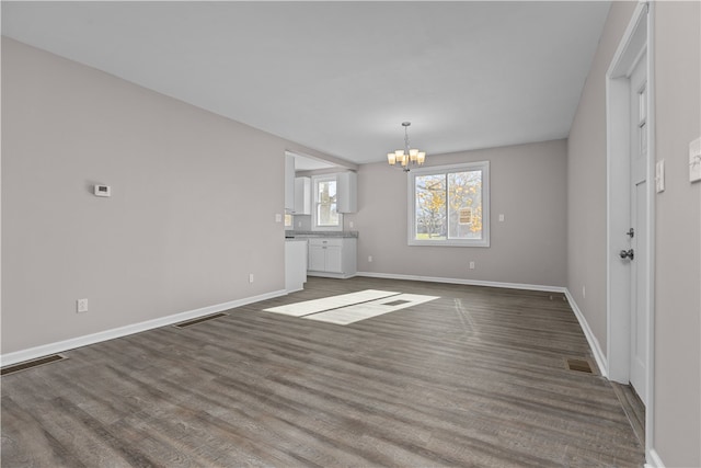 unfurnished living room featuring dark hardwood / wood-style flooring and an inviting chandelier