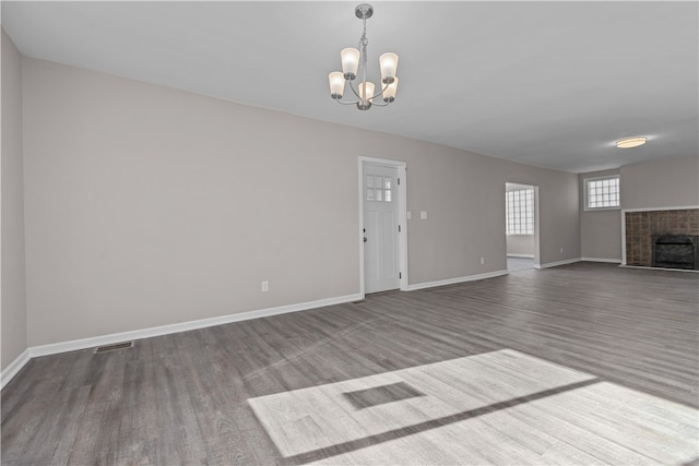 unfurnished living room featuring a tile fireplace, hardwood / wood-style floors, and a notable chandelier