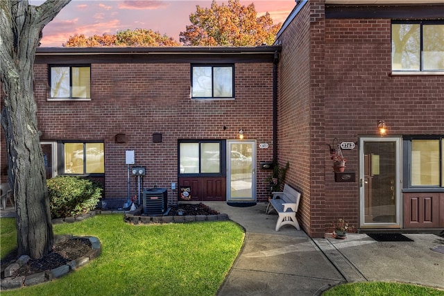 back house at dusk featuring a yard, a patio, and central AC