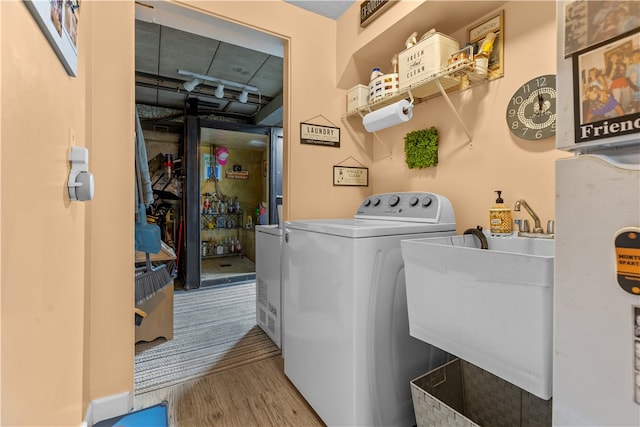 laundry area featuring hardwood / wood-style floors, washer / dryer, and sink