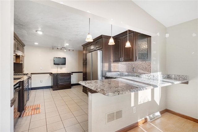 kitchen with light stone counters, kitchen peninsula, and hanging light fixtures