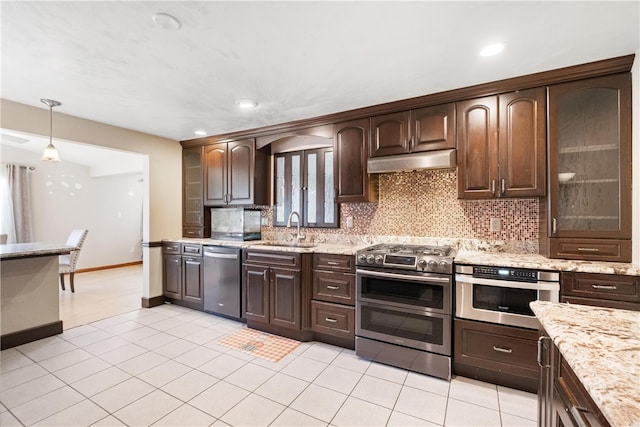 kitchen with decorative backsplash, dark brown cabinetry, stainless steel appliances, sink, and decorative light fixtures