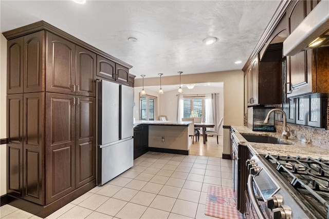 kitchen featuring sink, tasteful backsplash, light stone counters, pendant lighting, and appliances with stainless steel finishes