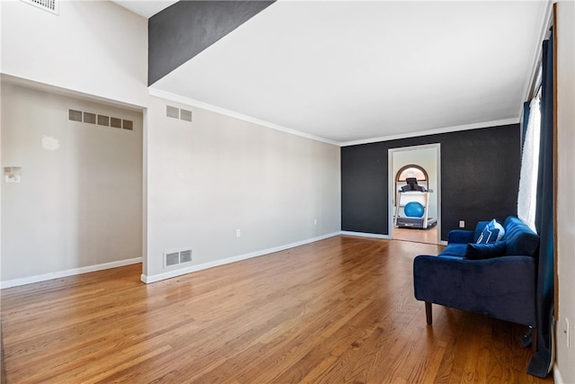 living area with crown molding and light hardwood / wood-style flooring