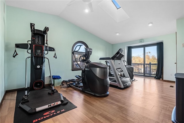 exercise room with hardwood / wood-style floors and vaulted ceiling with skylight