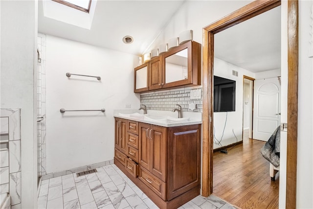 bathroom with a skylight, decorative backsplash, vanity, and hardwood / wood-style flooring