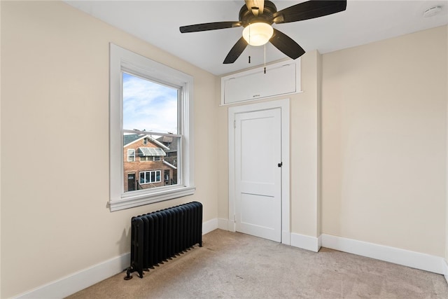 empty room with ceiling fan, radiator heating unit, and light colored carpet