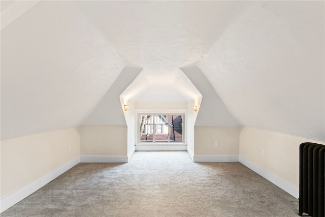 bonus room with a textured ceiling, light carpet, radiator, and vaulted ceiling