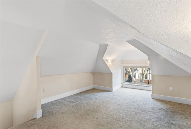 additional living space with lofted ceiling, a textured ceiling, and light carpet