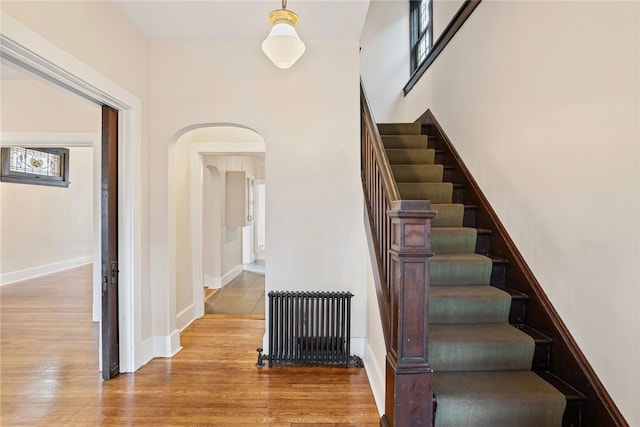 stairway with hardwood / wood-style flooring and radiator