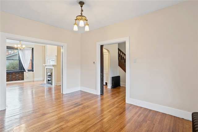 spare room with a notable chandelier and light hardwood / wood-style floors