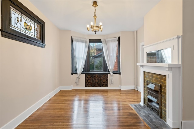 unfurnished living room with a fireplace, hardwood / wood-style flooring, and an inviting chandelier