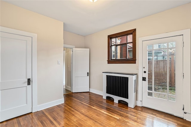 interior space with hardwood / wood-style flooring, plenty of natural light, and radiator heating unit