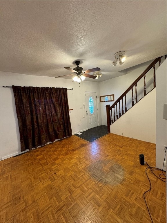 entrance foyer featuring ceiling fan, parquet floors, and a textured ceiling