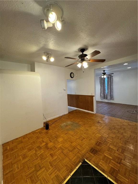 empty room featuring ceiling fan, parquet flooring, and a textured ceiling