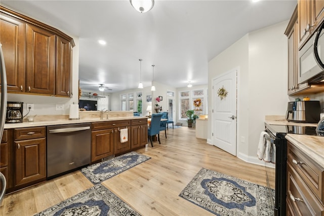 kitchen featuring sink, light hardwood / wood-style flooring, ceiling fan, decorative light fixtures, and stainless steel appliances