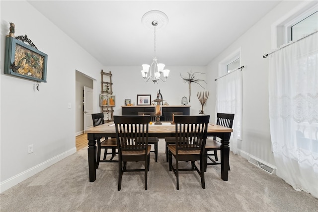 carpeted dining room featuring a notable chandelier