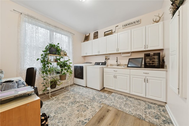 washroom featuring cabinets, separate washer and dryer, sink, and light hardwood / wood-style flooring