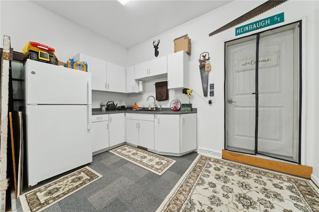 kitchen with dark colored carpet, white fridge, white cabinetry, and sink