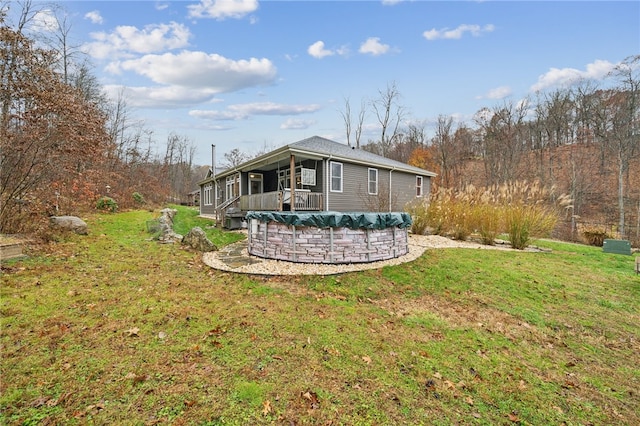 rear view of house with a lawn and a covered pool