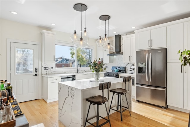 kitchen featuring wall chimney exhaust hood, black range with gas stovetop, pendant lighting, stainless steel fridge with ice dispenser, and white cabinetry