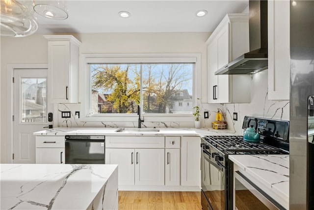 kitchen featuring black appliances, a healthy amount of sunlight, wall chimney range hood, and sink