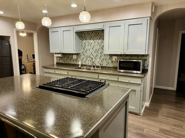 kitchen with appliances with stainless steel finishes, tasteful backsplash, sink, light hardwood / wood-style floors, and hanging light fixtures