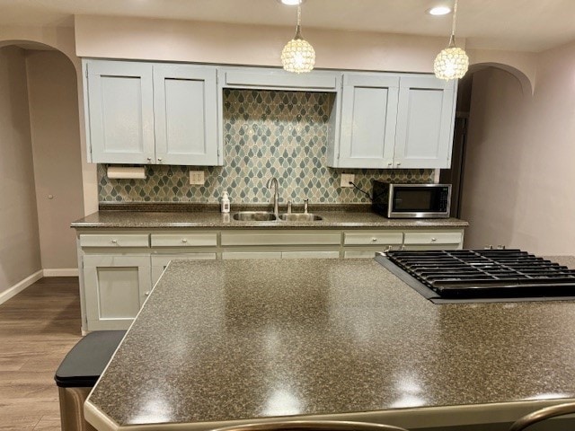 kitchen with decorative light fixtures, light wood-type flooring, stainless steel appliances, and sink