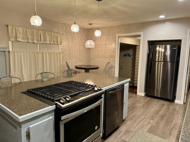 kitchen with pendant lighting, appliances with stainless steel finishes, and light hardwood / wood-style flooring