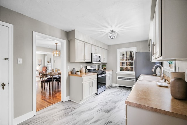 kitchen featuring white cabinets, sink, appliances with stainless steel finishes, and a chandelier