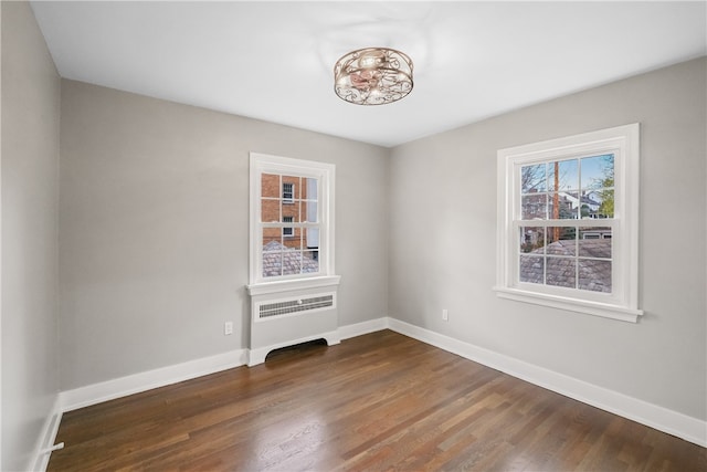 unfurnished room featuring radiator heating unit and dark hardwood / wood-style flooring