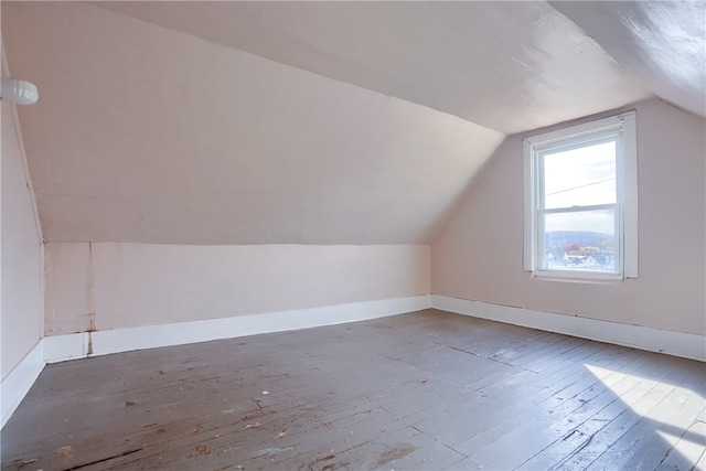 additional living space with hardwood / wood-style floors and vaulted ceiling