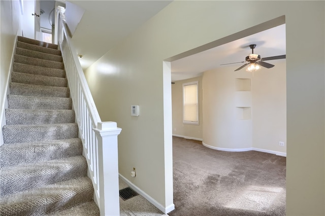 stairs with carpet flooring and ceiling fan