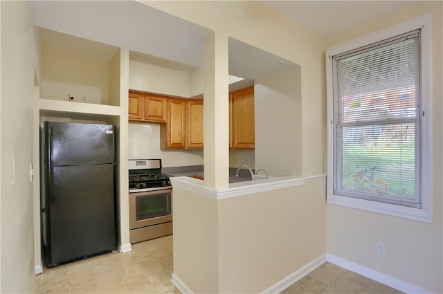 kitchen with kitchen peninsula, black fridge, and stainless steel gas range