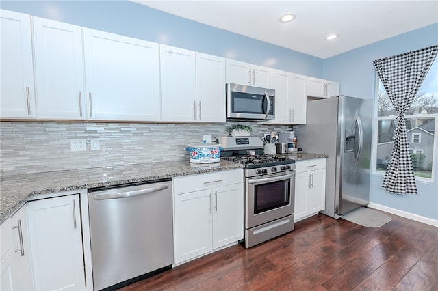 kitchen featuring light stone countertops, dark hardwood / wood-style floors, backsplash, white cabinets, and appliances with stainless steel finishes