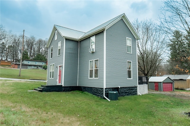 view of home's exterior with a lawn, central AC unit, an outdoor structure, and a garage