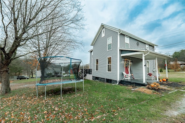 rear view of house featuring a lawn and a trampoline